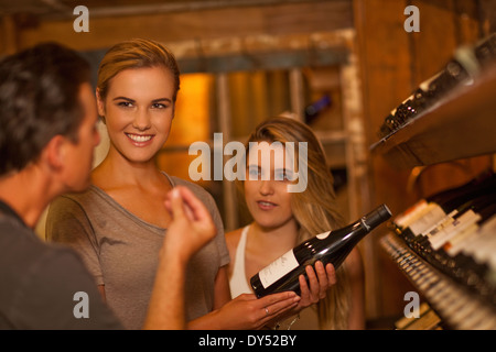 Two young women choosing wine in wine shop Stock Photo