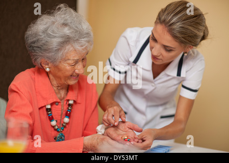 Care assistant handing medication to senior woman Stock Photo