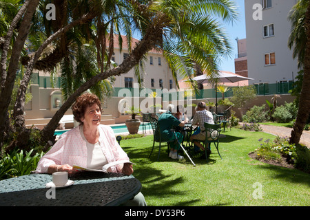 Senior woman having coffee in garden of retirement villa Stock Photo