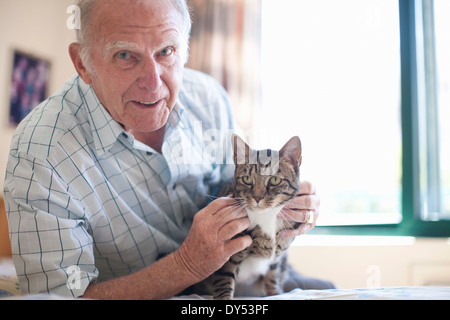 Portrait of senior man petting domestic cat Stock Photo