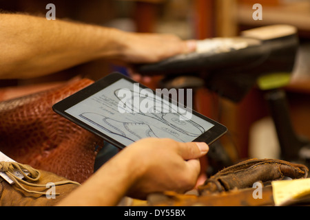 Cobbler holding digital tablet Stock Photo