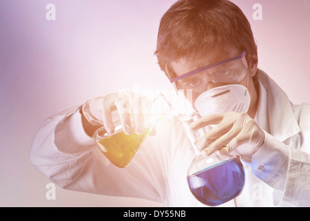 Young scientist carefully mixing flasks of liquid Stock Photo