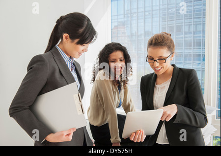 Three businesswomen sharing ideas on digital tablet Stock Photo