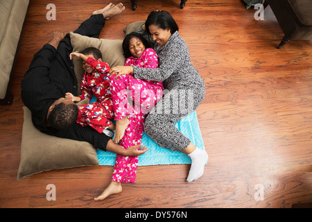 Mid adult couple and children playing on floor cushions