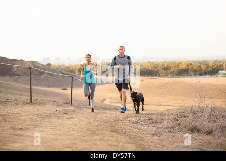 Couple running with dog Stock Photo