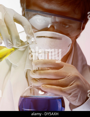 Young scientist carefully pouring liquid from flask Stock Photo