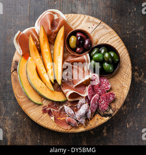 Antipasto ham, melon and olives on wooden background Stock Photo