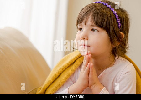 Young girl sitting on sofa daydreaming Stock Photo