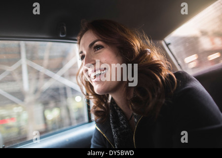 Happy young woman in back seat of taxi