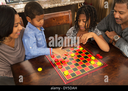 Mid adult couple and children playing draughts at dining table Stock Photo