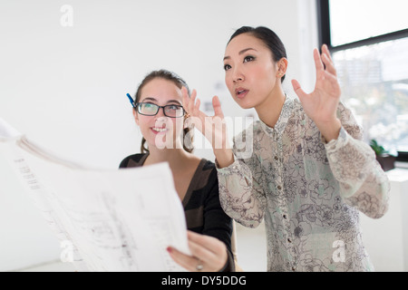 Two female colleagues discussing blueprint Stock Photo