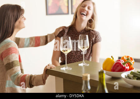 Mid adult female friends laughing in kitchen Stock Photo