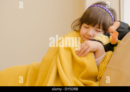 Young girl lying on sofa pretending to sleep Stock Photo