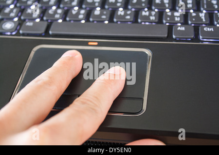 a hand is touching the laptop touchpad Stock Photo