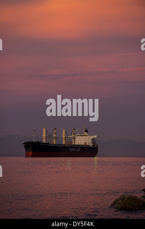 Freighter anchored in Burrard inlet in an early morning sunset. Stock Photo