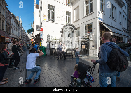 BRUSSELS, Belgium — Tourists pose for photographs with the famous Manneken Pis fountain at the corner of Rue de l'Étuve/Stoofstraat. The iconic bronze statue, a replica of Hiëronymus Duquesnoy the Elder's 1619 original, remains one of Brussels' most popular tourist photography locations. Visitors gather at this historic corner to capture images with the whimsical fountain that has become a symbol of Brussels' cultural heritage. Stock Photo