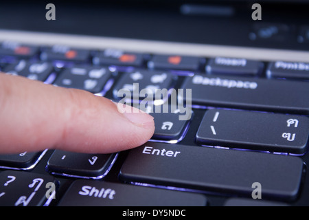a finger is pushing the enter button Stock Photo