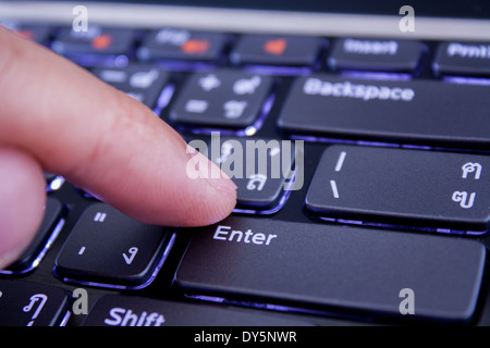 a finger is pushing the enter button Stock Photo