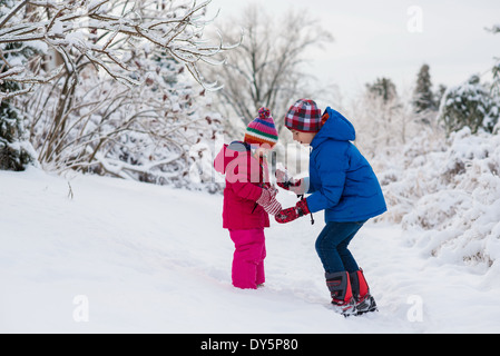 Brother showing icicles to sister whilst out in snow Stock Photo