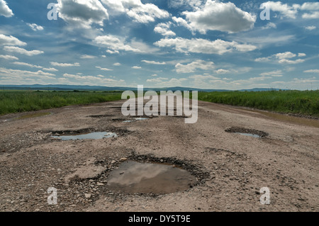 puddle on old cracked road Stock Photo