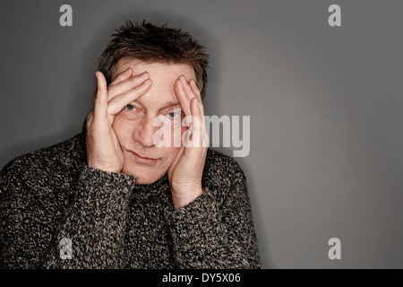Man a bit stressed with head in his hands looking at camera Stock Photo