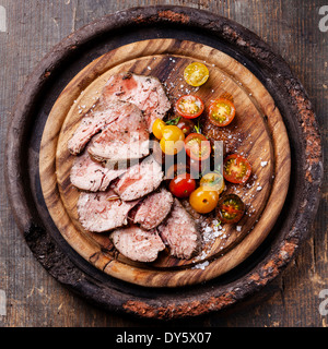 Roast beef with cherry tomatoes on cutting board Stock Photo