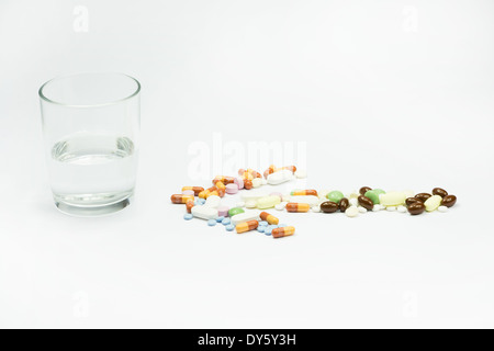 arrow pills near a cup of water on white background Stock Photo