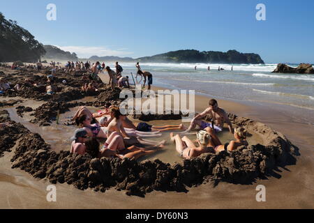 Tourists relaxing in hot pools dug on beach, Hot Water Beach, Coromandel Peninsula, Waikato, North Island, New Zealand, Pacific