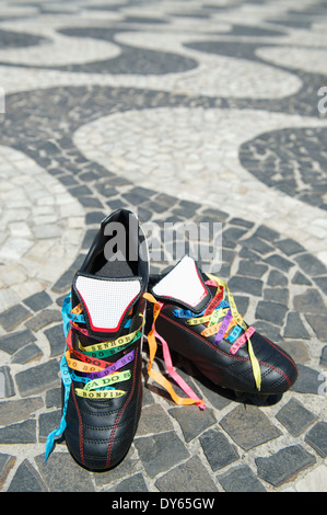 Good luck soccer football boots soccer cleats laced with Brazilian wish ribbons on the Copacabana Beach sidewalk Rio de Janeiro Stock Photo
