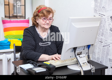 Senior woman typing keyboard button on computer Stock Photo