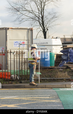 Construction work surveyor using a stadia rod or levelling rod as part of a surveying work at a construction site in England. Stock Photo