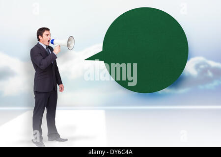 Composite image of standing businessman shouting through a megaphone with speech bubble Stock Photo