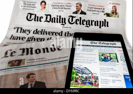 Tablet with online international news on top of British Daily Telegraph and French Le Monde newspapers on white background Stock Photo - Alamy
