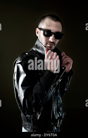 Young man in leather jacket and sunglasses looking at camera Stock Photo