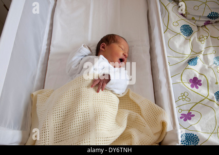 Three day old newborn baby girl in her crib yawning Stock Photo