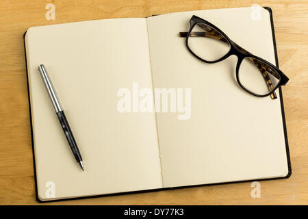 Overhead of open notebook with pen and glasses Stock Photo