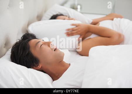 Woman covering her ears as partner is snoring loudly Stock Photo