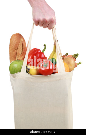 Hand holding a shopping bag filled with groceries such as fruits and vegetables, isolated on white Stock Photo