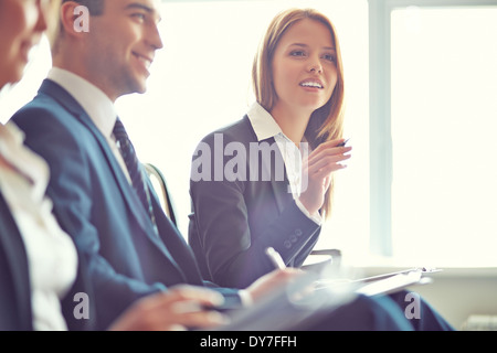 Smart businesswoman asking question at seminar with her colleagues near by Stock Photo