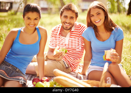 Group of young friends eating sandwiches at picnic in the country Stock Photo