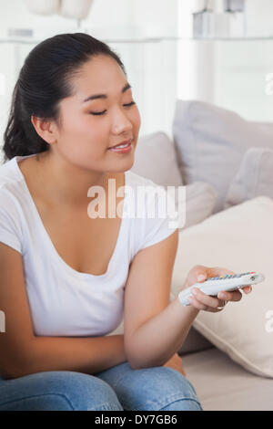 Happy woman sitting on couch watching tv Stock Photo