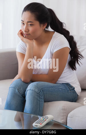 Bored woman sitting on couch Stock Photo