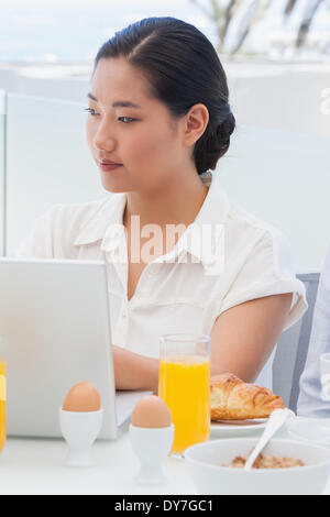 Woman using her laptop at breakfast Stock Photo