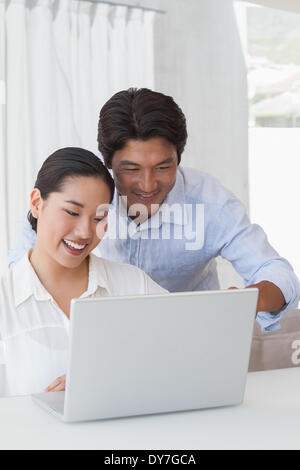 Happy couple using laptop together Stock Photo