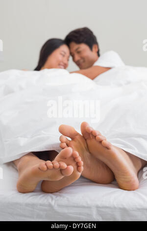 Couples feet sticking out from under duvet Stock Photo