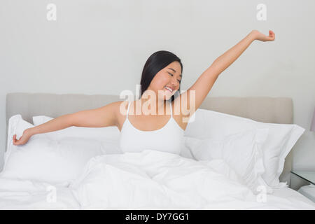 Smiling woman stretching in bed in the morning Stock Photo