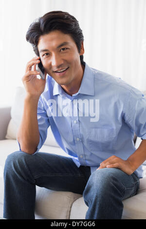 Happy man sitting on couch talking on phone Stock Photo
