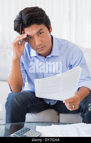 Man sitting on couch working out his finances Stock Photo