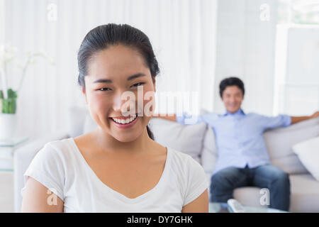 Happy woman smiling at camera with boyfriend in back Stock Photo