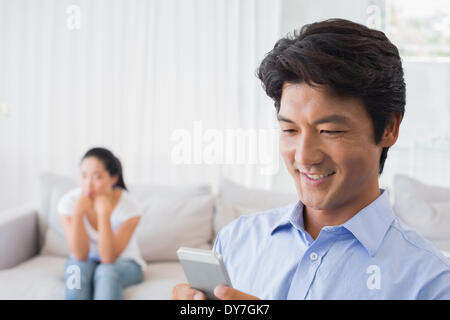 Man sending a text while girlfriend watches from couch Stock Photo